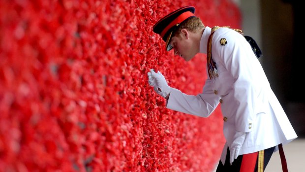 Prince Harry places a poppy at the Roll of Honour during a visit to the Australian War Memorial on April 6, 2015 in Canberra.