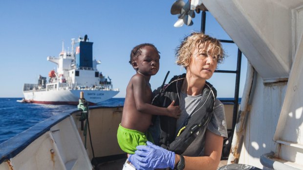 A Spanish nurse of Proactiva Open Arms NGO carries a child rescued from the Mediterranean Sea aboard the Golfo Azzurro ship, operated by Proactiva.