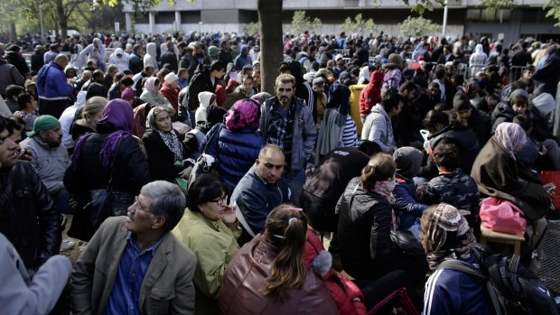 Hundreds of migrants and refugees wait for Berlin's State Office of Health and Welfare in Berlin, Germany, last year.