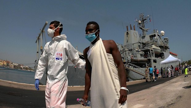 An Italian paramedic helps a migrant during the disembark of 402 migrants from the Britain Royal Navy's ship Echo in the harbour of Brindisi, Italy, on Friday.