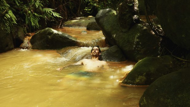 Mitchell Johnson swims in the hot springs during the Australian team's visit to Trafalgar Falls on Sunday.