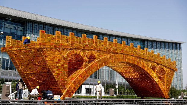 Workers install a 'Golden Bridge of Silk Road' structure outside revealed at the time of China's Belt and Road Forum in Beijing in April.