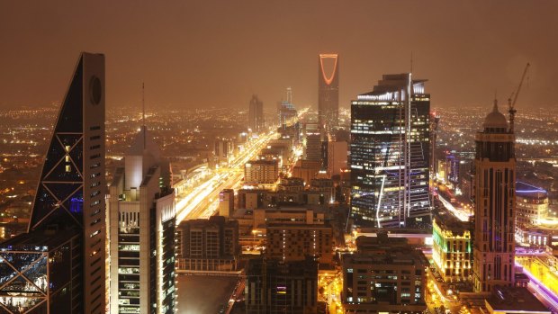 The kingdom Tower, centre rear, stands illuminated by light as  traffic moves along the King Fahd highway in Riyadh.