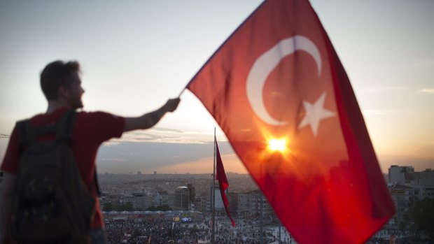 A protester waves the Turkish flag from a rooftop at Istanbul's Taksim Square in June 2013.