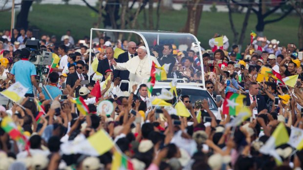 Pope Francis, standing at right on pope-mobile, greets Christians upon his arrival for a holy Mass in Yangon, Myanmar, on Wednesday.