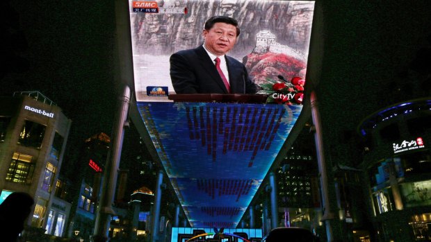 A huge screen shows a broadcast of  Xi Jinping speaking in Beijing's Great Hall of the People. 