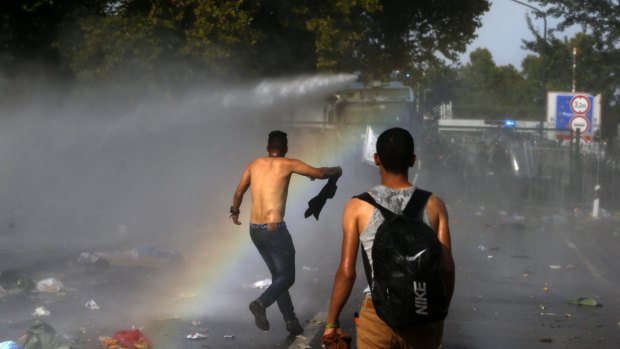 Hungarian police spray water on migrants at the border crossing with Serbia.