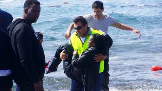 A man carries a migrant from the Aegean sea, in the eastern island of Rhodes.