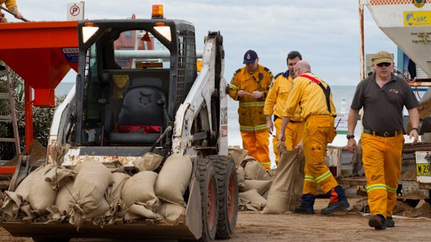 Workers commence a sandbagging operation on Tuesday to try to stop the collapse of an apartment building.