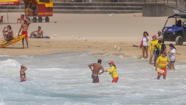 A surfer is helped ashore after losing his board at Maroubra.