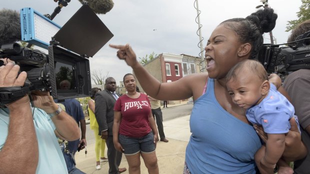 Massieka Holness, with her four-month-old son Tavon, reacts after prosecutors dropped all charges against police in Baltimore.