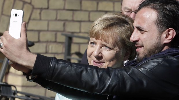An unidentified man takes a selfie with Angela Merkel, left, during her visit at a migrant registration centre in Berlin in September.