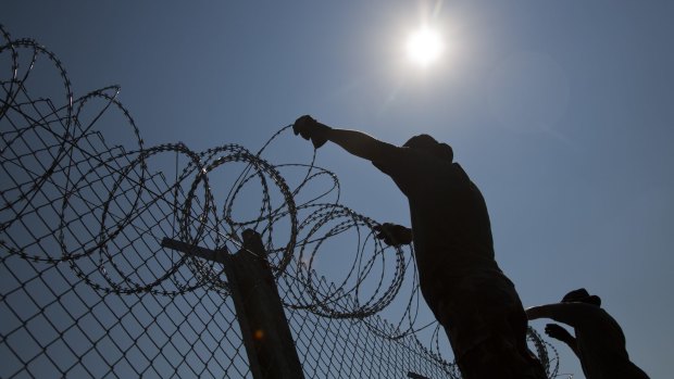 Hungarian soldiers put up razor wire on top of a fence on the border with Serbia, in Asotthalom, Hungary.