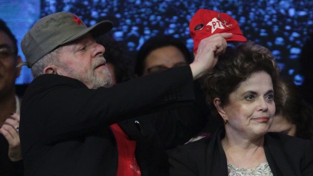 Former Brazilian President Luiz Inacio Lula da Silva, left, puts a Workers Party cap on ousted President Dilma Rousseff earlier this month.