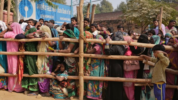 Indians stand in a queue to deposit and exchange discontinued currency notes outside a bank in Allahabad, India.