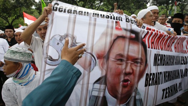 Protesters hold a banner calling for the arrest of  Ahok, depicted with fangs and horns, outside City Hall in Jakarta.