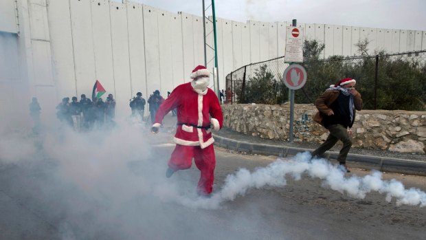 A Palestinian protester dressed as Santa Claus runs to avoid tear gas during clashes in the West Bank city of Bethlehem.