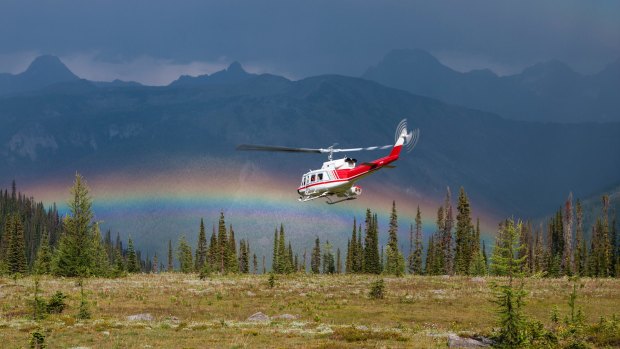 A helicopter flies towards a rainbow on a CMH heli-hiking trip in Canada's Bugaboos.