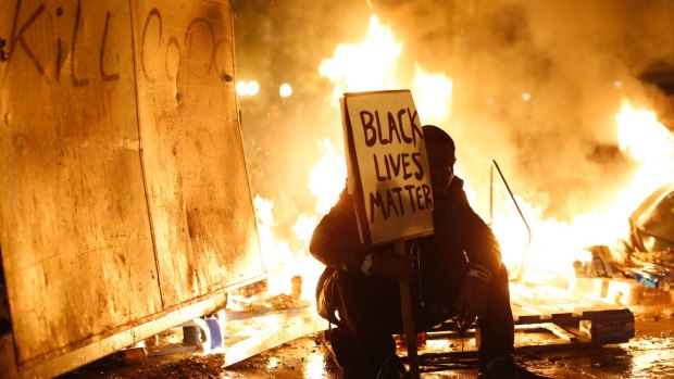 Ferguson burning: A demonstrator sits in front of a street fire during a Ferguson demonstration in Oakland, California.