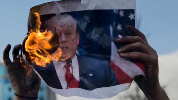 Palestinian protesters burn a poster with a picture of Trump.