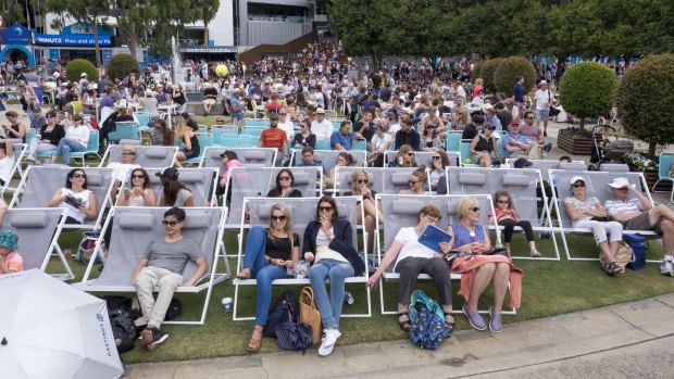 People relax as they watch the tennis at the big screen at Melbourne Park.