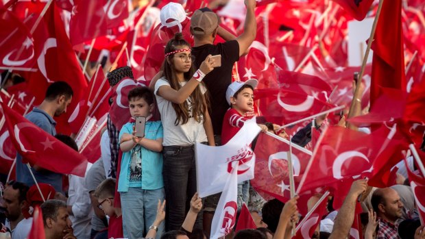 Children photograph the massive crowd as they wait for official ceremonies to begin on the renamed July 15 Martyrs Bridge in Istanbul.