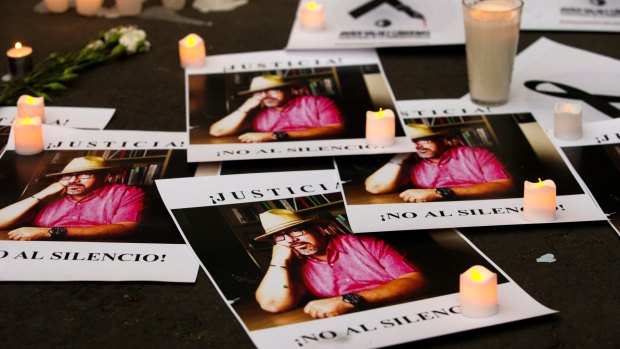 Candles adorn posters with a picture of murdered journalist Javier Valdez and the words "Justice! No to silence!" during a demonstration outside the Interior Ministry in Mexico City.