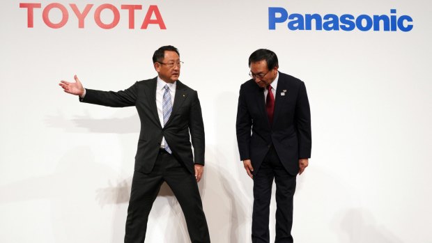 Toyota President Akio Toyoda, left, escorts Panasonic President Kazuhiro Tsuga, after they announced they are considering developing batteries for electric vehicles together.