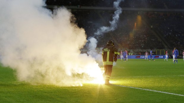 A firefighter removes a flare thrown by Croatia supporters.