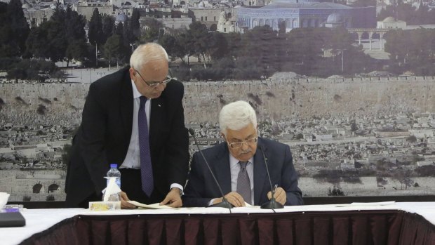 Palestinian Authority President Mahmoud Abbas (right) signs international agreements handed to him by chief Palestinian negotiator Saeb Erekat.