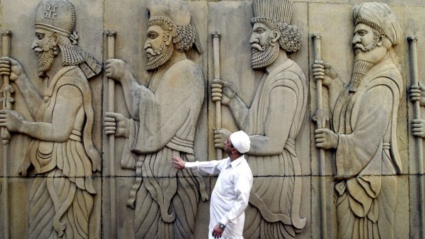 A Parsi priest reverently touches the statues, believed to be of ancestors, outside a Fire Temple in Mumbai, India.