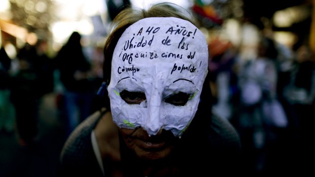 A demonstrator wears a mask that reads in Spanish: "At 40 years! Unity of people's organisations" in Bariloche, Argentina.