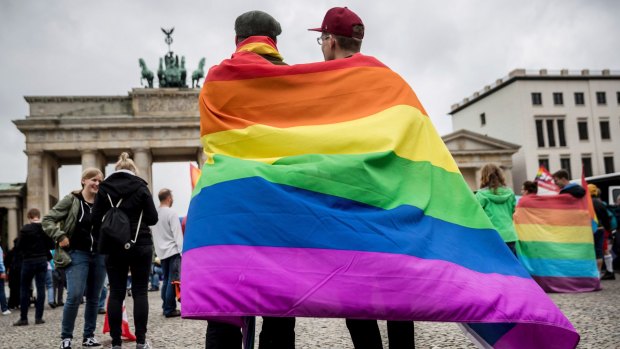 Men with rainbow flags stand in front of the Brandenburg Gate to celebrate the legalisation of same-sex marriage in Berlin on June 30.