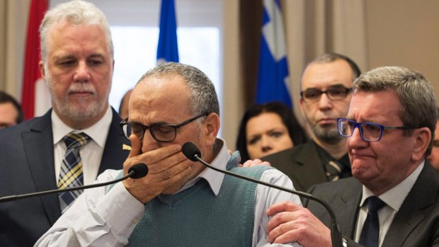 Mohamed Labibi, president of the Islamic cultural centre, is comforted by Quebec Premier Philippe Couillard, left, and Quebec City mayor Regis Labeaume, right.