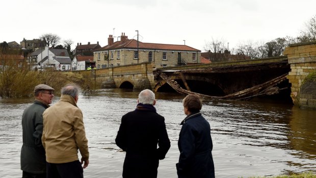 Residents look on Wednesday at the bridge that collapsed due to flooding in Tadcaster, northern England, on Tuesday.