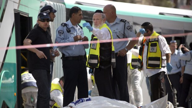 Israeli emergency response members stand next to the body of an Israeli victim.