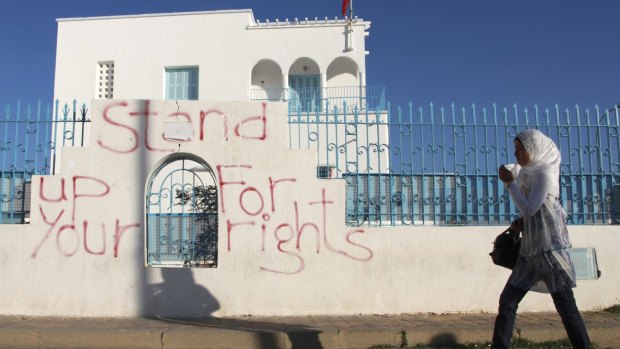 A woman walks past graffiti in Sidi Bouzid, Tunisia.  