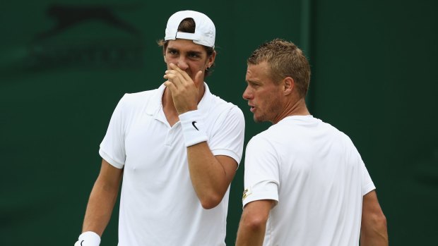Leyton Hewitt (right) talks to his partner Thanasi Kokkinakis in their first-round match against Marin Draganja of Croatia and Henri Kontinen of Finland during day four of Wimbledon.
