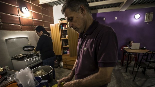 Juan Suarez and his wife, Carmen Lara, cook dinner in their home in a government housing project in Caracas. 