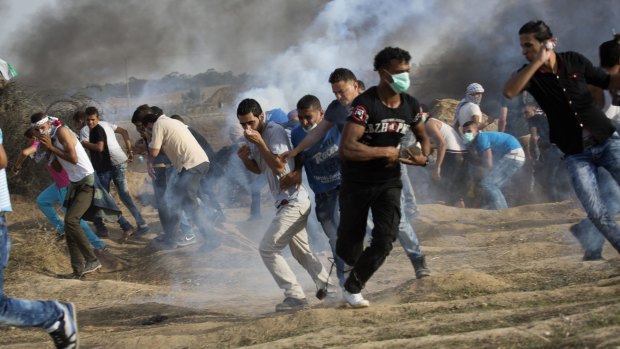 Palestinian protesters run for cover from tear gas fired by Israeli soldiers during clashes on the Israeli border with Gaza on Friday. 