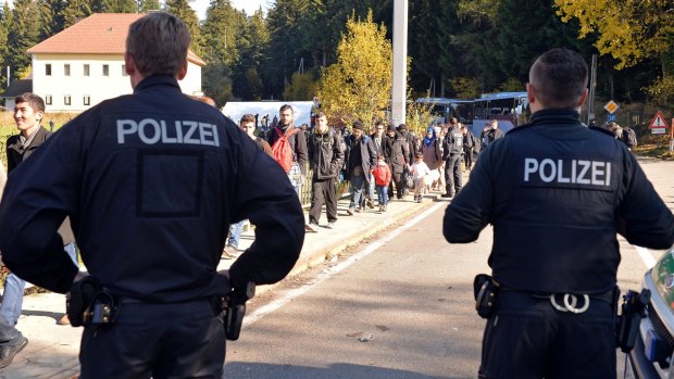 German police officers watch migrants crossing the border between Austria and Germany on Wednesday.