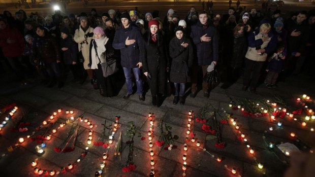 Mourners sing the Ukrainian national anthem next to candles forming the name of Mariupol in Kiev's Independence Square.