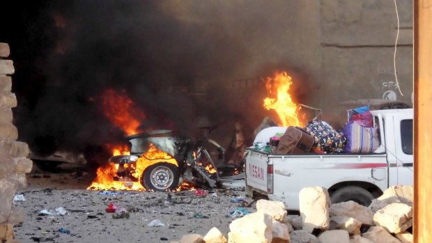 A car is engulfed by flames during clashes in Ramadi.