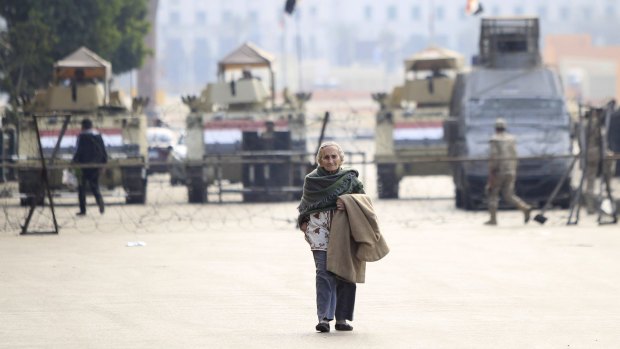A lone woman crosses the entrance to Cairo's Tahrir Square, which was blocked by military vehicles and barbed wire on Sunday during the fourth anniversary of the 2011 Egyptian uprising.