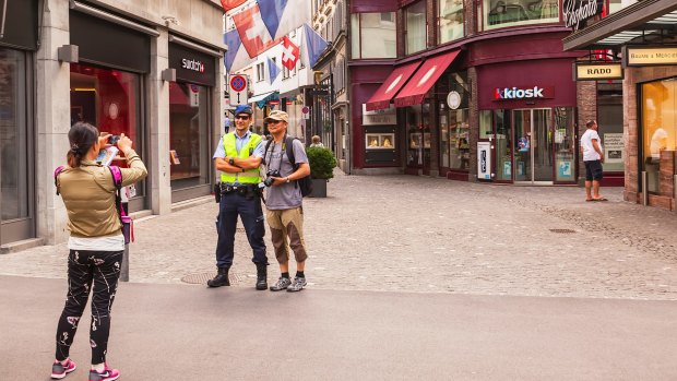 Tourists take photos with a policeman in Zurich. Lonely Planet's guide to Switzerland suggests police there engage in racial profiling.