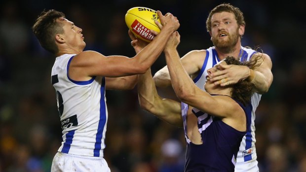 Docker Nat Fyfe is challenged by North Melbourne's Ben Jacobs and Lachlan Hansen.