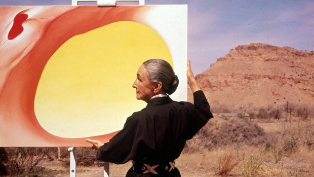 American artist Georgia O'Keeffe (1887 - 1986) stands at an easel outdoors, adjusting a canvas from her 'Pelvis Series- Red With Yellow,' Albuquerque, New Mexico, 1960. 