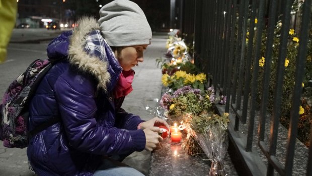 A woman lights a candle to pay tribute to victims of a Russian plane crash, outside the Russian Embassy in Kiev, Ukraine.