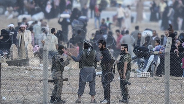 Islamic State fighters discuss the situation at the border fence. It is believed that 150 IS fighters are holding Tal Abyad against Kurdish militia and US-led air strikes.