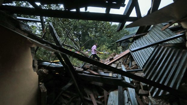 Ruined: A man passes a damaged house at the site of the landslide.